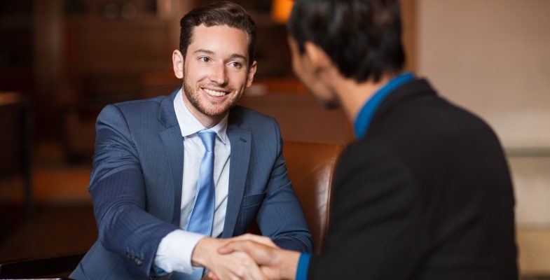 two-happy-partners-shaking-hands-in-cafe